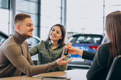 young couple talking with a salesperson in car showroom